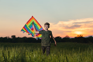 A child plays with a kite at sunset in the field.