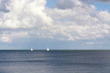 View on two sailingboats on the Gouwzee, near Volendam and the IJsselmeer in the Netherlands. A perfect summer day with typical dutch weater with clouds, sun and blue sky.