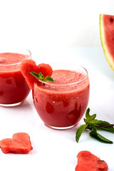 Watermelon smoothie fresh juice with mint and pieces in the shape of hearts on a white background. Summer healthy drinks.
