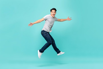 Fototapeta na wymiar Energetic happy young Asian man in casual clothes jumping