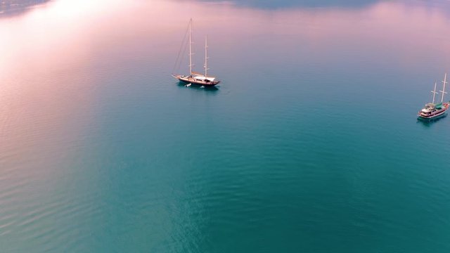 Aerial drone flight over the Mediterranean sea during the colorful sunset in Turkey . Ship, yachts and gulets are on the water.