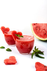 Watermelon smoothie fresh juice with mint and pieces in the shape of hearts on a white background. Summer healthy drinks. Copy space.