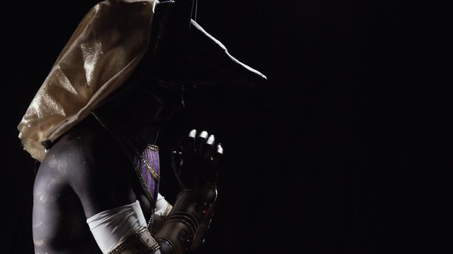 Ancient egyptian god Anubis is rubbing his hands in the dark, profile shot