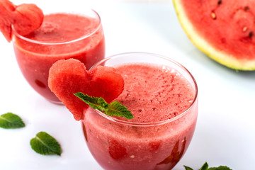 Watermelon smoothie fresh juice with mint and pieces in the shape of hearts on a white background. Summer healthy drinks. Close-up.