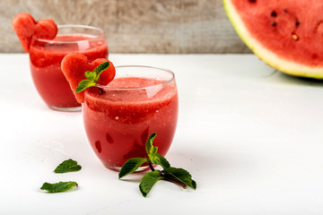 Watermelon smoothie fresh juice with mint and pieces in the shape of hearts on a white background. Summer healthy drinks.