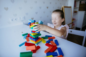Child playing with colorful wooden bricks on the white table background. Kid building with geometric shapes. Learning and education concept