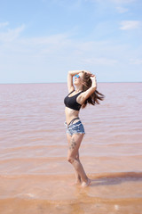 Fototapeta na wymiar Young sexy fit curvy woman posing near the pink lake