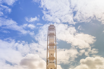 Ferris wheel on the colorful cloudy sky. Background concept of happy holidays time.