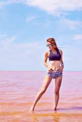 Young sexy fit curvy woman posing near the pink lake