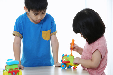 Cute little boy and girl is playing service tools with toy airplane . A toddler working with toy tools. A little craftsman.