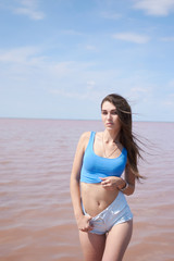 Fototapeta na wymiar Sexy young woman posing near the pink lake