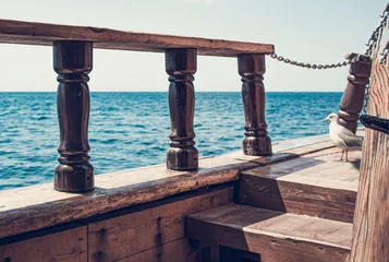  Uitzicht vanaf het oude houten schip aan de horizon van de zee. Zeemeeuw op het schip. Vintage schip met oude attributen, zoals in de tijd van piraten. © OleJohny