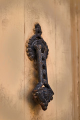Vintage and rusty knocker on a wooden door