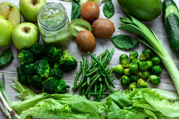 Fresh green food on a light table. Avocados cucumbers cabbage apples beans kiwi onions broccoli. The concept of healthy food, detox vegetarianism. Copy space flat lay.