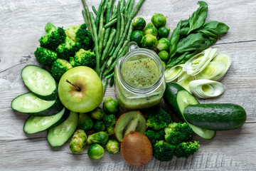 Fresh green food on a light table. Avocados cucumbers cabbage apples beans kiwi onions broccoli. The concept of healthy food, detox vegetarianism. Copy space flat lay.