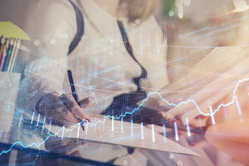 A woman hands writing information about stock market in notepad. Forex chart holograms in front. Concept of research.