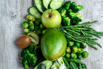 Fresh green food on a light table. Avocados cucumbers cabbage apples beans kiwi onions broccoli. The concept of healthy food, detox vegetarianism. Copy space flat lay.