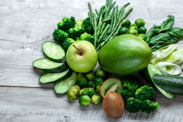 Fresh green food on a light table. Avocados cucumbers cabbage apples beans kiwi onions broccoli. The concept of healthy food, detox vegetarianism. Copy space flat lay.