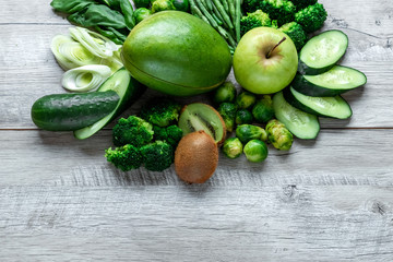 Fresh green food on a light table. Avocados cucumbers cabbage apples beans kiwi onions broccoli. The concept of healthy food, detox vegetarianism. Copy space flat lay.