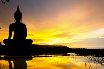 Silhouette largest statue Buddha image in the sunset over the hill, Water reflection in the middle of the rice field  background in Thailand - Asia - obrazy, fototapety, plakaty