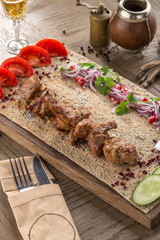 chicken shish kebab on lavash bread with fresh cucumber and tomato on wooden table