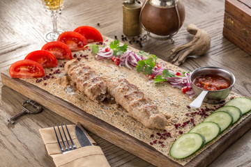Homemade chicken Kofta kebabs on lavash bread with fresh tomato and cucumber on wooden table