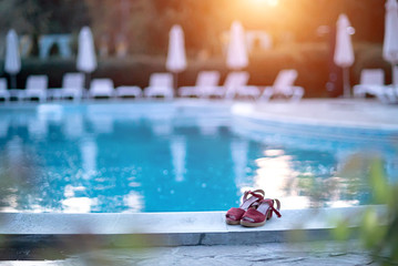 Red women shoes on the edge of a luxury pool