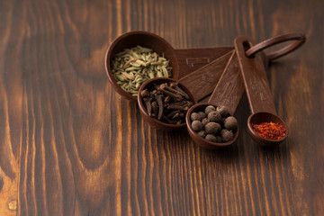 Set of spices - black pepper peas, clove, hot red pepper and exotic spice at the  measuring spoons. dark wood background 