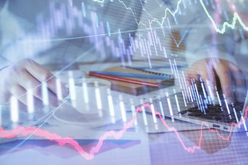 Forex graph with businessman working on computer in office on background. Concept of hardworking. Double exposure.