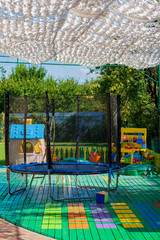 Trampoline on the playground for children. A cozy corner in the yard for children’s games