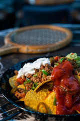 Nachos served tomato sauce and meat with blurred restaurant background