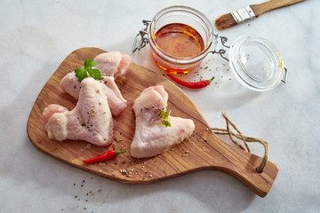 Two uncooked chicken wings on a wooden board