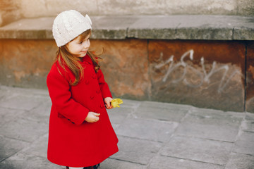 little beautiful girl in red beret and red coat walking in the autumn city with a bouquet of yellow tulips