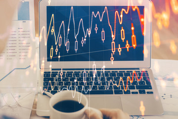 Stock market chart hologram drawn on personal computer background. Double exposure. Concept of investment.
