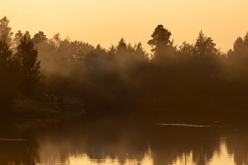 Creeping smoke over a calm lake at sunset
