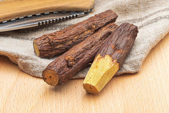 Group of stick licorice bars (natural root licorice). Paloduz or Licorice Plant (Glycyrrhiza glabra, orozuz). Peeled with razor. On wooden background and rustic look.