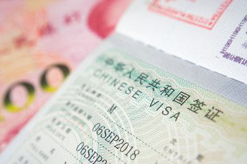 Chinese Visa in a passport with RMB on a background