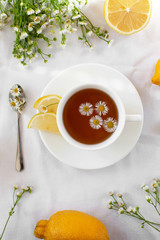 Treating a cold or flu. Traditional medicine, hot tea with herbs and lemon. Chamomile tea. A light still life in the style of Provence. Flat lay, selective focus.