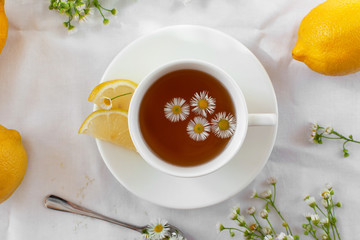 Treating a cold or flu. Traditional medicine, hot tea with herbs and lemon. Chamomile tea. A light still life in the style of Provence. Messy scene. Flat lay, selective focus.