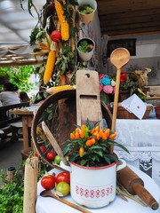 Rustic or vintage kitchen utensils and vegetables, tomatoes, sweet orange mini peppers, corn and succulents in vintage pots as fall or autumn home decoration or decor
