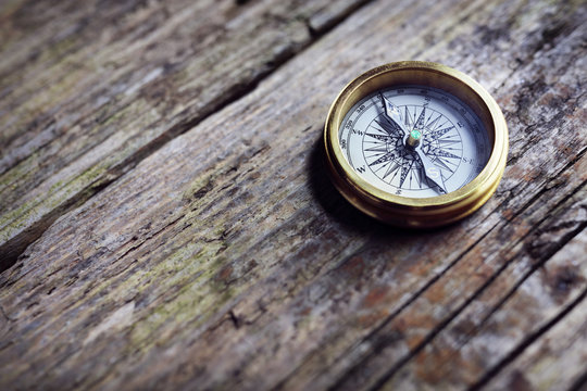 Antique golden compass on wood background