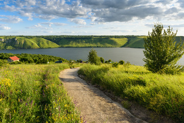 Scenic landscape of trail going through meadow with lush herbs and wildflowers down to river. Beautiful nature of Dniester river and Bakota area, part of the National Park "Podolski Tovtry" in Ukraine © GarkushaArt