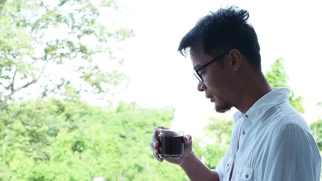 Business man wearing a white shirt  Standing on the balcony and drinking black coffee. Concept  Relax in working hours.