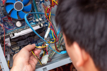 The young technician hold the screwdriver for repairing the computer in his hand. Computer...