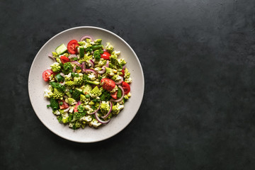 Organic fresh romanesco cabbage salad with vegetables on black background. Top view. 
