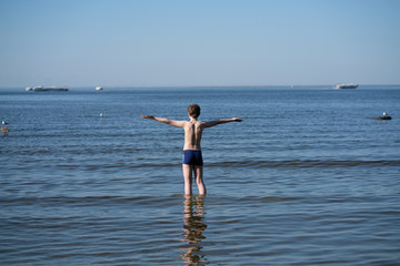 Silhouette of child on the beach, holding his hands up