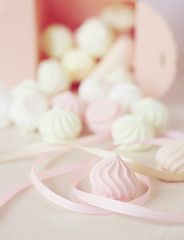 Pastel romantic background with scattered little meringues in a box, flower and ribbons
