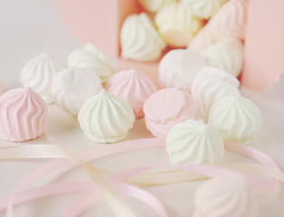 Pastel romantic background with scattered little meringues in a box, flower and ribbons