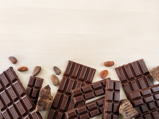 Chocolate bars, сhocolate beans, pieces of chocolate scattered on a light background