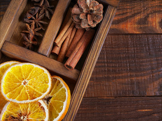 Christmas holiday composition : Beautiful close-up  of dry Oranges, Cinnamon sticks and star Anis, fir cones in  a wooden box on the wooden background. Top view. Flat lay